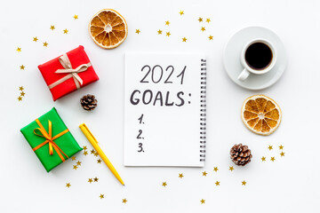 Top view of 2021 goals list with decorations and notebook on a table, flat lay