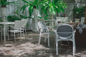 Fototapeta na wymiar A white Metal outdoor garden furniture, table and chair set in the home small garden under the tree shade with the afternoon light.