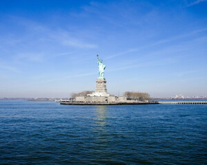 Statue of Liberty in NY Harbor on bright sunny day with blue sky