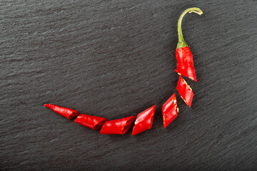 Red chili pepper on a black slate board.
