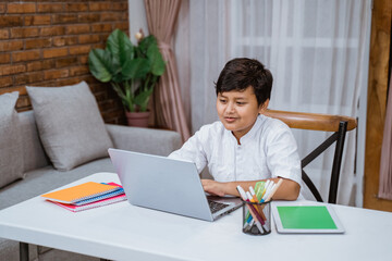 smiling boy doing homework at home with laptop and tablet digital
