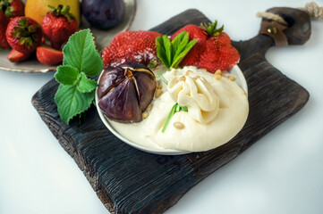 Buratta with strawberries and figs, baked in the oven with pine nuts. Buratta with fruit is a gourmet dish. Ways to serve soft Italian cheeses