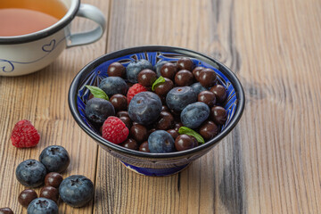 Blackberries coated with milk chocolate in a blue ceramic bow