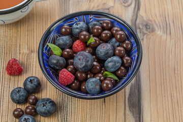 Blackberries coated with milk chocolate in a blue ceramic bow