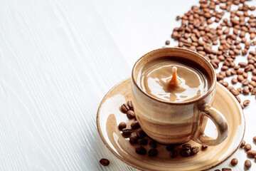 Latte and coffee beans on a white wooden table.