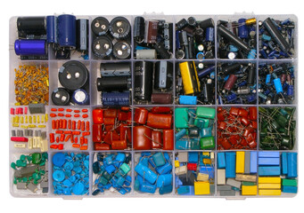 A set of different capacitors in a plastic case. Electronics on white background
