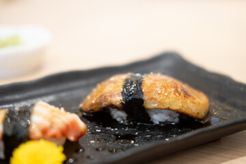 Grilled foie gras sushi on black plate.