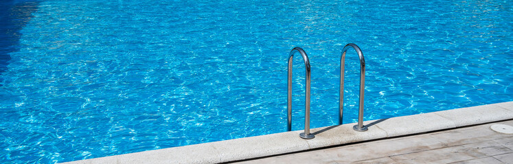 Close up grab bars ladder in the blue swimming pool outdoors