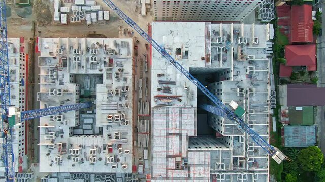 Aerial view of the ongoing developing buildings, big cranes and heavy equipment at a construction site