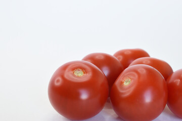 Several tomatoes are lying one after another on a white surface.