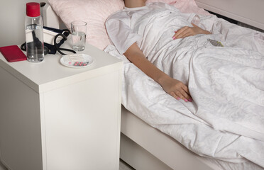 bedside table with medicines and water. The papacy is self-isolating at home.Girl with  cold at home under the covers