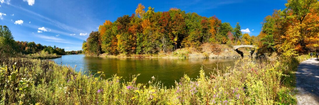 Panoramic view of Beebe Lake, with Sackett`s Bridge, foliage trees and trail path, in Ithaca, New York. Beebe Lake is a sanctuary of water, woods, and wetlands in the the heart of the Cornell Campus. 