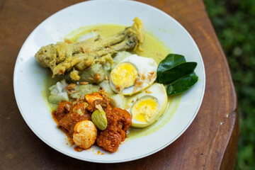Top view of a plate of chicken braised coconut milk served on a wooden table at home, A popular dish for Ramadan