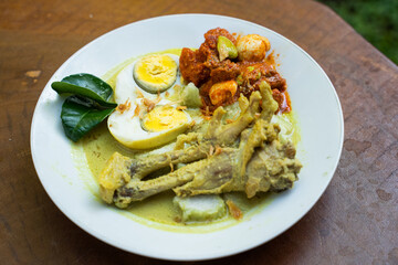 A plate of Opor Ayam or chicken braised coconut milk served on a wooden table at home