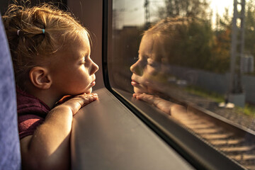 Little girl looking out the train window at sunset