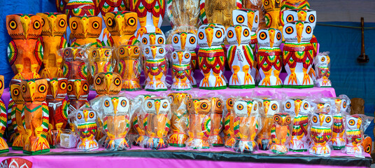 A collection of colorful handmade traditional wooden owl sculpture and toys are displayed for selling in handicraft fair.