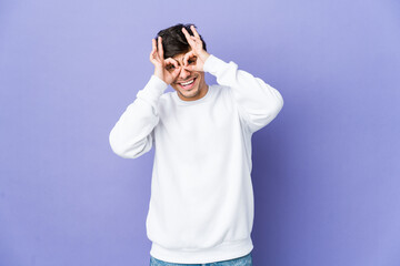 Young cool man showing okay sign over eyes