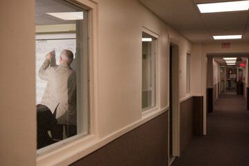 College instructor writing on whiteboard through corridor window