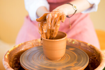 hands sculpts cup from clay pot. Workshop of modeling on potter wheel.