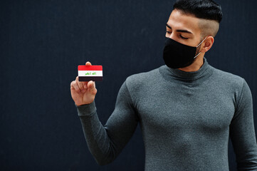 Middle eastern man in gray turtleneck and black face protect mask show Iraq flag isolated...