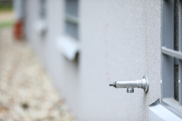 Metal water tap in a grey building. Faucet in a residential building.