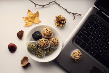 a set of kinds of hand made sweets next to laptop decorated with golden leaves, cones and branch