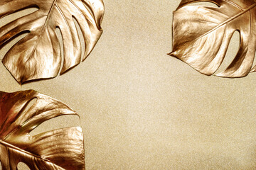 Golden monstera leaf on shiny glittering background. Clean minimal flat lay design. Tropical gold foliage for trendy christmas and new year eve holiday layout. Luxury fashion lifestyle concept. © hitdelight