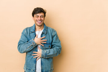 Young cool man laughs happily and has fun keeping hands on stomach.