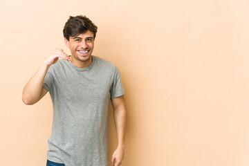 Young cool man laughing about something, covering mouth with hands.