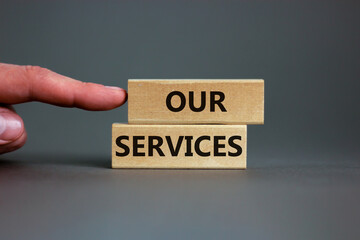 Wooden blocks with the text 'our services' on beautiful grey background. Male hand. Business concept, copy space.
