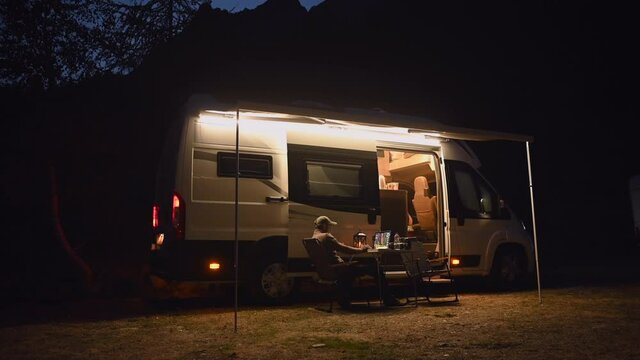 Caucasian Men in His 40s and the Late Evening On-line Remote Work in Front of Modern Camper Van While on Camping