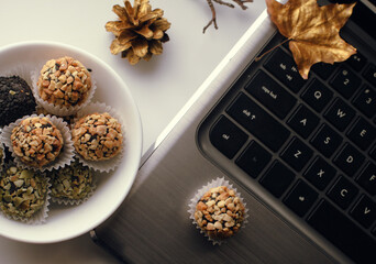 hand made sweet candies in a bowl next to laptop decorated with golden leaves and cones