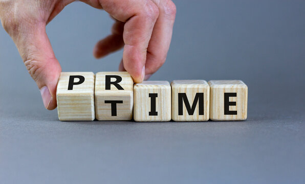Hand flips a cube and changes the word 'prime' to 'time' or vice versa. Beautiful grey background. Business concept. Copy space.
