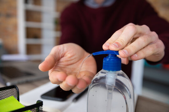 Mid section of man sanitizing his hands