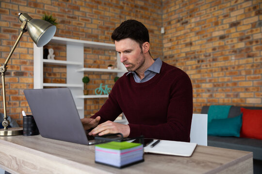 Man using laptop while sitting on his desk
