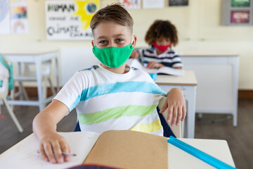 Portrait of boy wearing face mask sitting in class at school