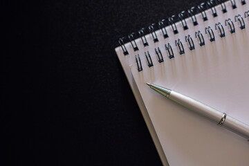 Close up of Pen and Notebook on black background table ,Concept of education,blank copy space, math, cost, tax or investment .