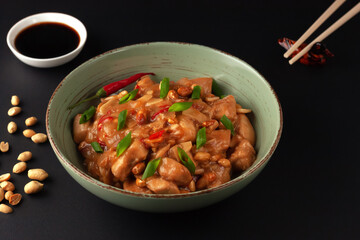 Kung Bao chicken on a black background. A Chinese dish with chicken, chili, peanuts, sauces and onions.