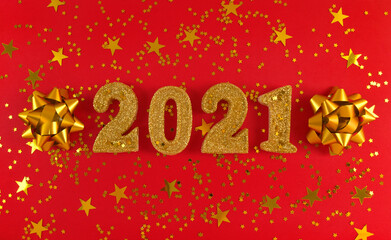 Greeting card of New Year 2021. Golden glittered figures, stars and bows on a red background.