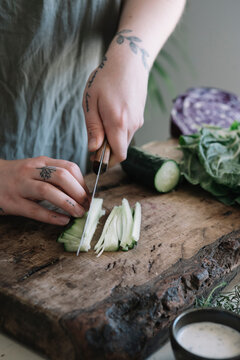Young woman cutting cucumber on cutting board