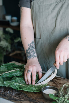Young woman cutting pak choi on chopping board