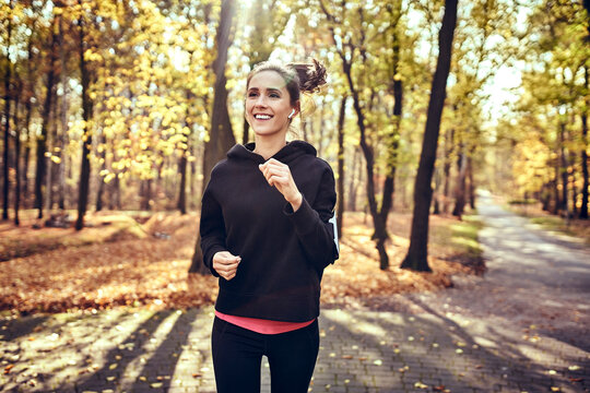 Young Woman Jogging In Autumn Forest