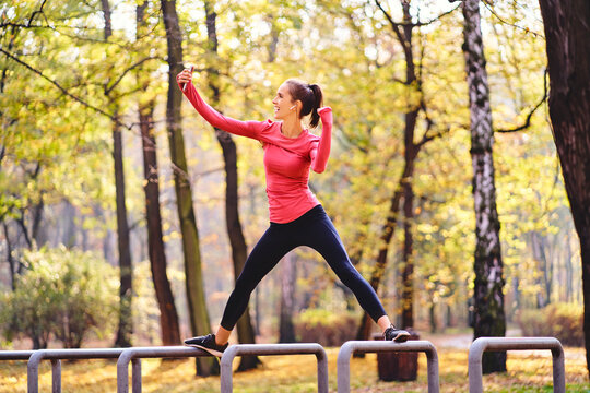 Young female jogger taking a selfie on bicycle stand in autumn forest