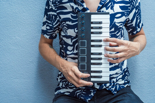 Man playing midi keyboard while sitting against wall