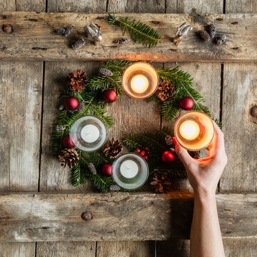 Hand of woman touching glass cover of candle burning on Advent wreath