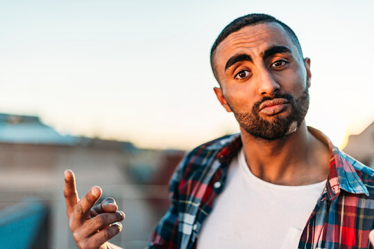 Man showing peace sign while standing on rooftop against clear sky