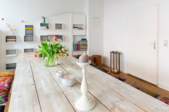 Flower vase and candle on wooden table