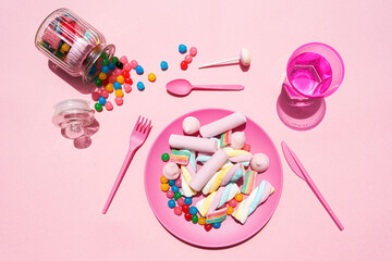 Studio shot of glass of water, jar of candies and plastic plate filled with various sweets