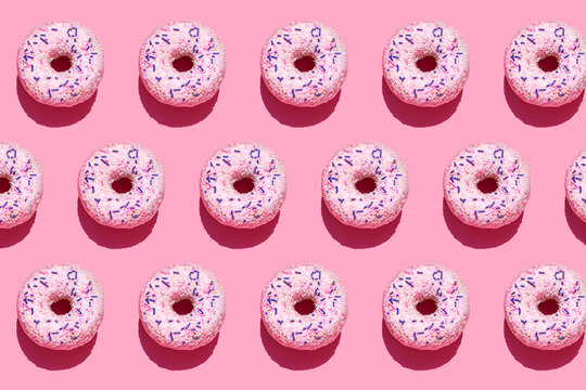 Pattern of sweet doughnuts against pink background