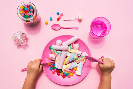 Hands of baby girl preparing to eat plate filled with various sweets